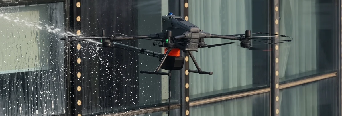 Dron myjący szklaną elewację budynku biurowego